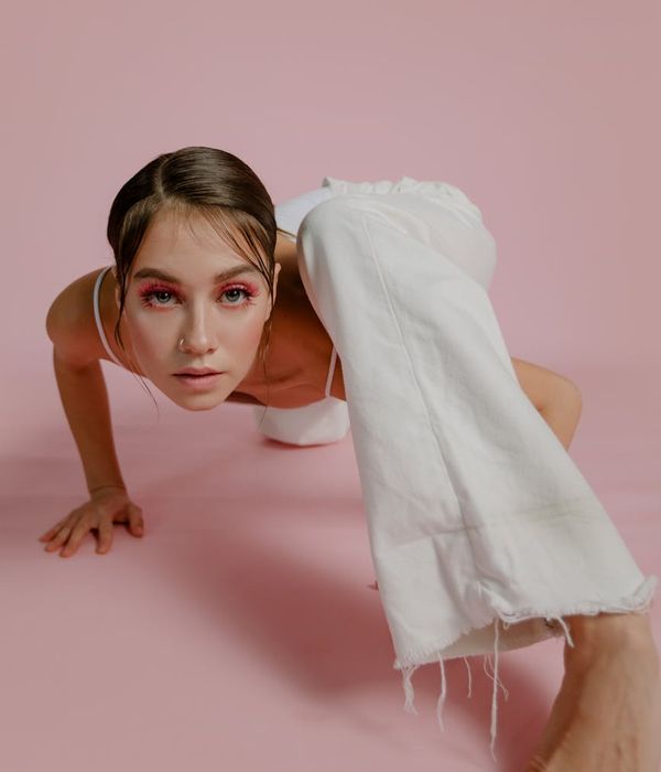 Woman in a dynamic stretching pose feeling energetic against a lilac mist background.